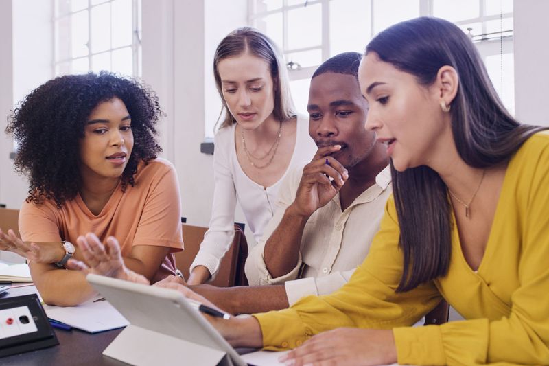 Students discussing work on a shared tablet computer