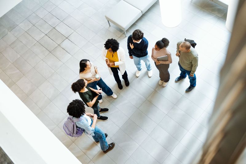 Students chatting with eachother in a half circle in a lobby viewed from above