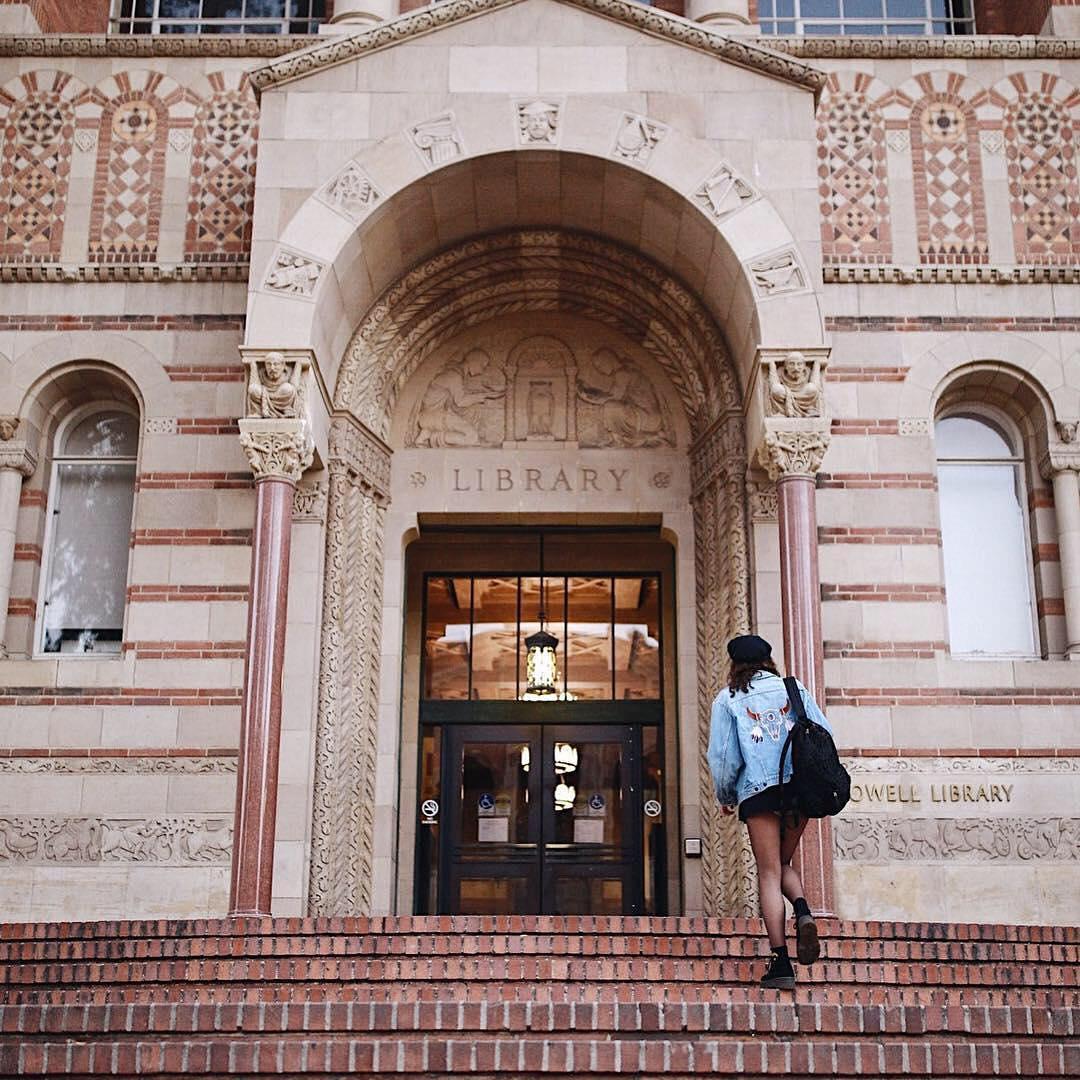 A student walks up the steps to the entrance of Powell Library