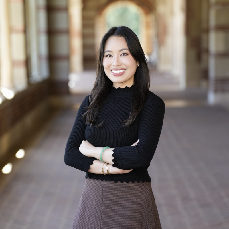 Headshot of white woman with black hair wearing a black blouse and gray skirt