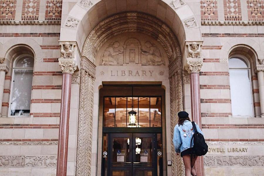 A student walks up the steps to the entrance of Powell Library